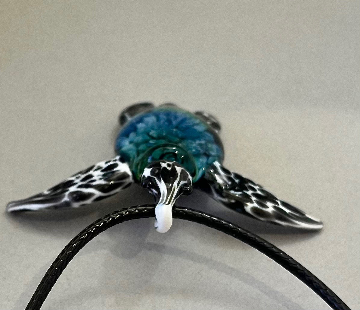glass black and white spotted sea turtle pendant with iceberg style explosion in the shell at a 270 degree angle.