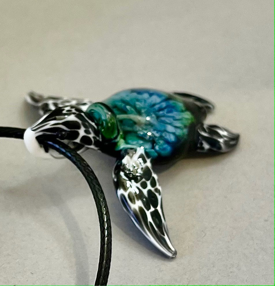 glass black and white spotted sea turtle pendant with iceberg style explosion in the shell at a 210 degree angle.