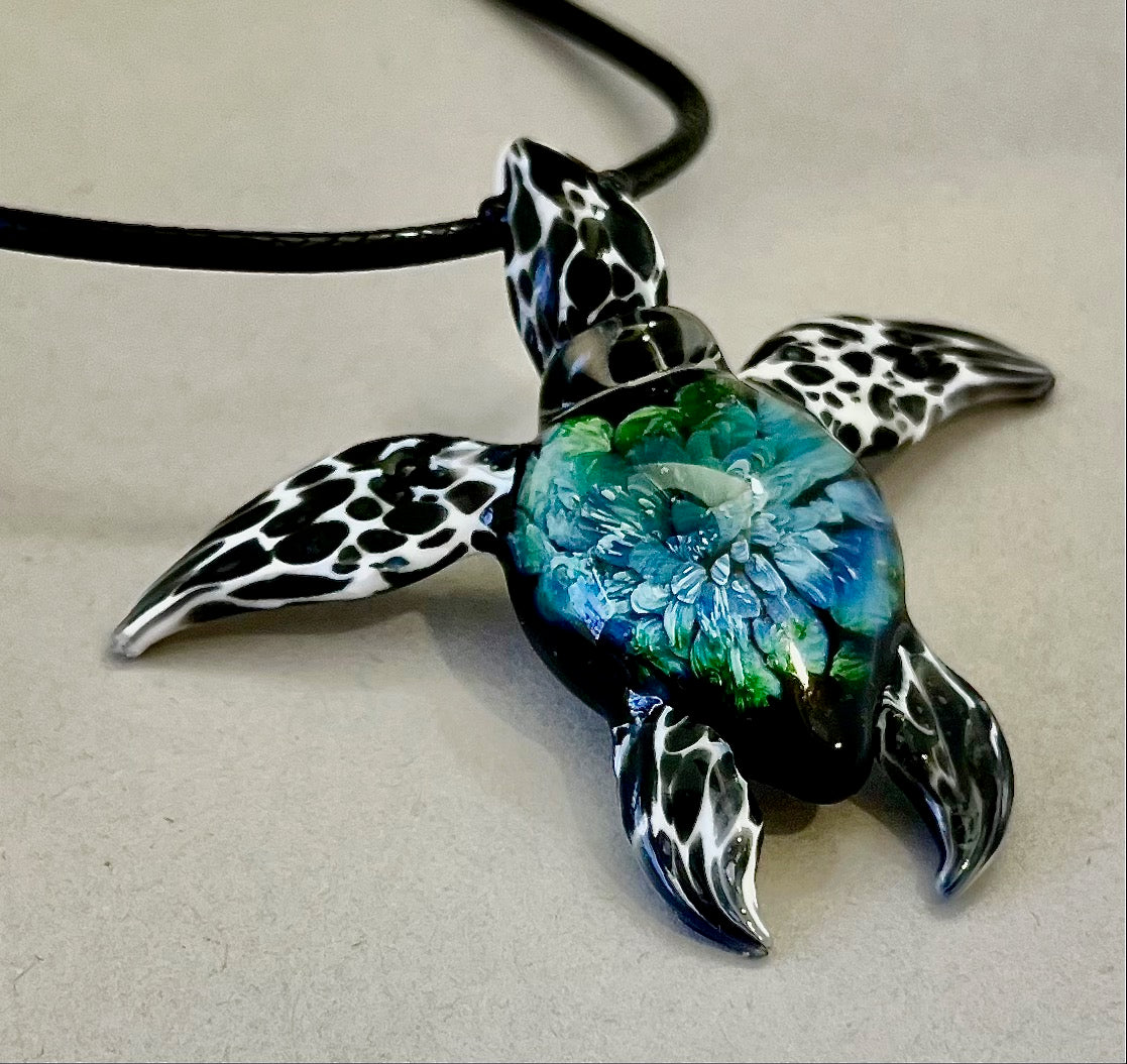 glass black and white spotted sea turtle pendant with iceberg style explosion in the shell at a 120 degree angle.
