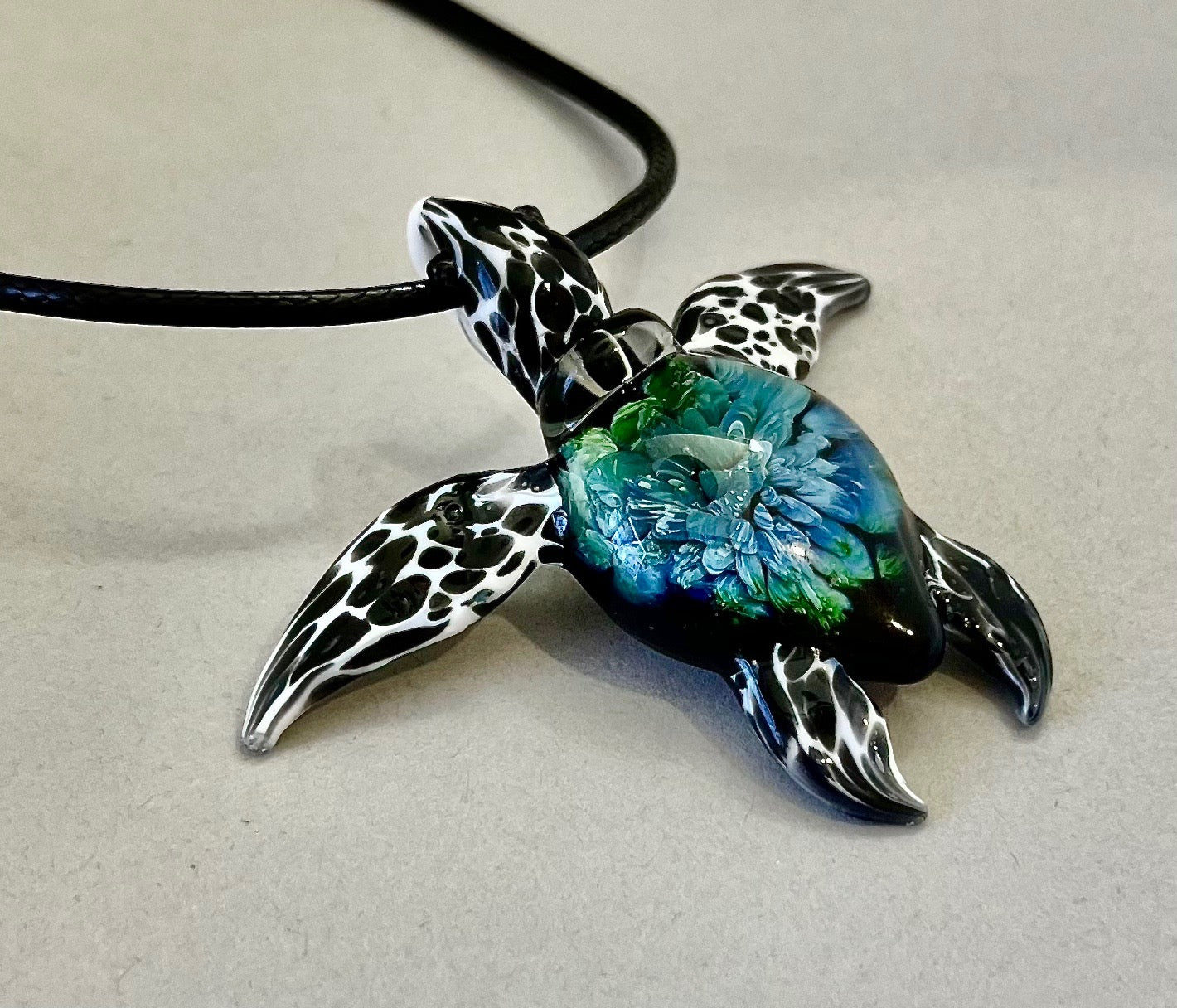 glass black and white spotted sea turtle pendant with iceberg style explosion in the shell at a 135 degree angle.